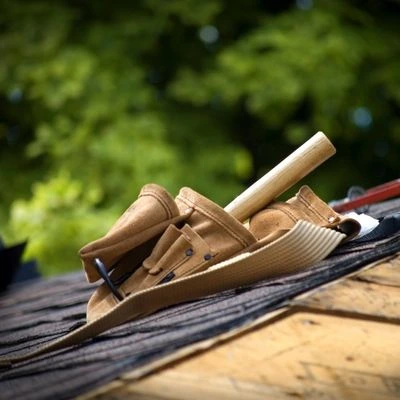 Roofing tool belt resting on a partially shingled roof