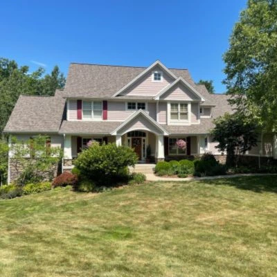 A beautifully maintained two-story home with a newly installed roof under a clear blue sky.