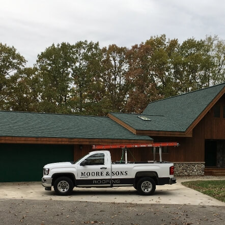 A new home build with a roof installed by Moore and Sons Roofing.  There is a company vehicle in front of the home.