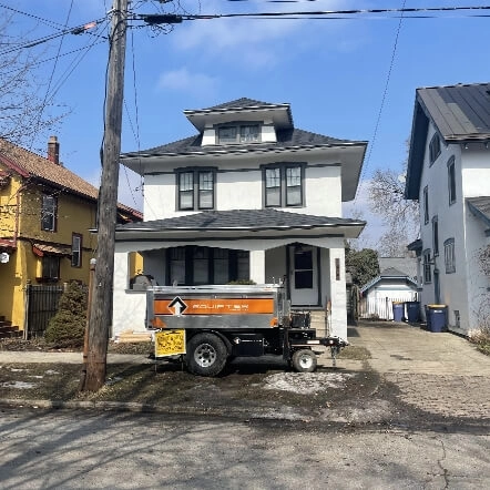 A white two story home with a roof repair by Moore and Sons Roofing